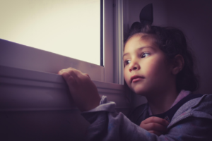 A child sitting quietly by a window in natural light, reflecting inner awareness and emotional presence.
