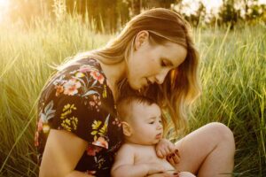 A parent holding a baby calmly in nature, supporting emotional safety, regulation, and inner trust.